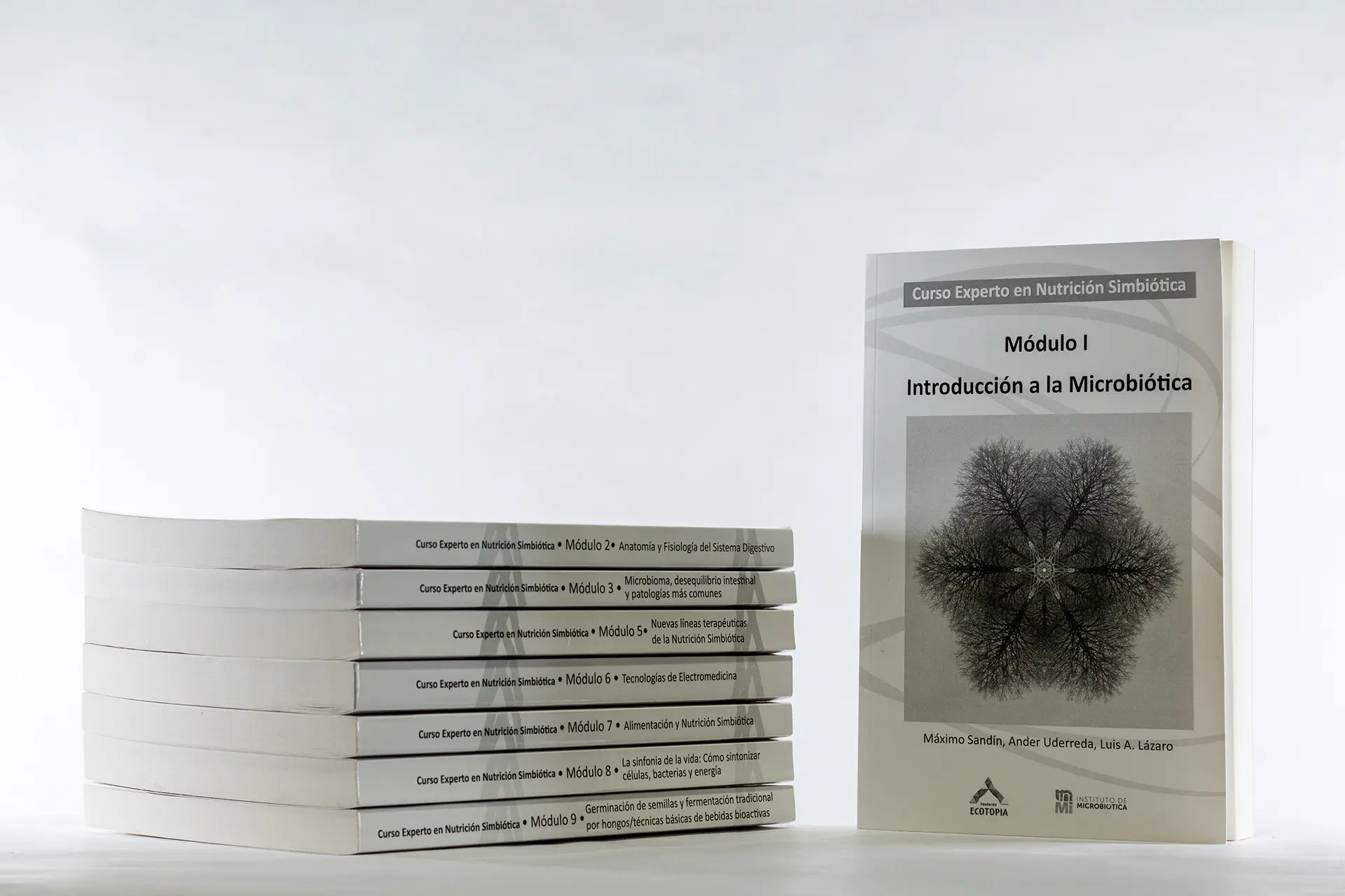 Los manuales del Curso Experto en Nutrición Simbiótica, apilados junto al manual del Módulo 1